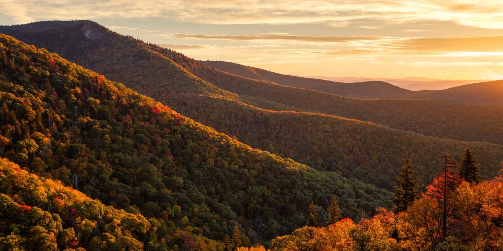 Sunset over rolling forested mountain landscape.